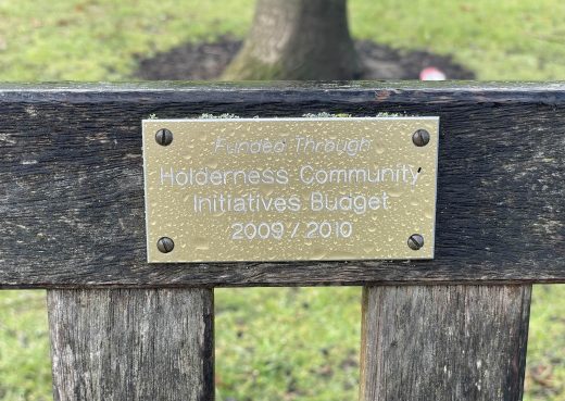 Commemorative plaque on a wooden memorial bench