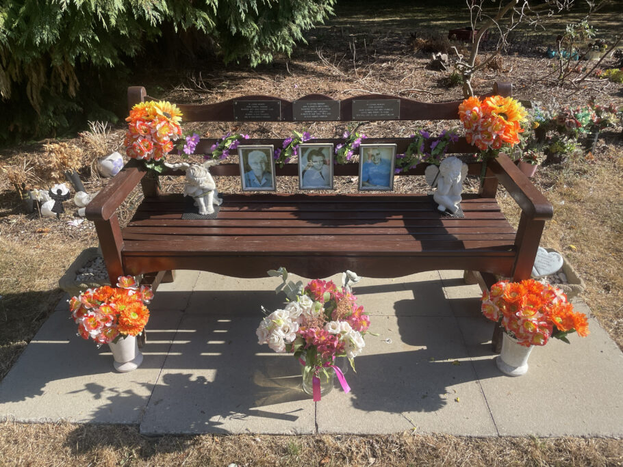 A preserved Beverley Memorial bench adorned with flowers and tributes at the Chanterlands Crematorium