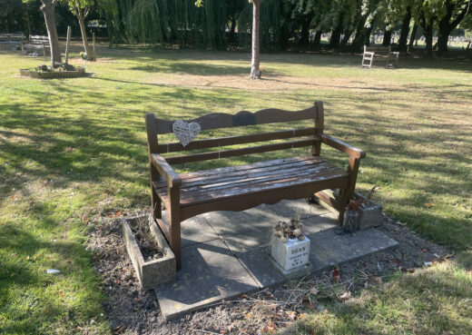 Long-standing wooden memorial bench with heart decoration and personal memorials at Chanterlands Crematorium.