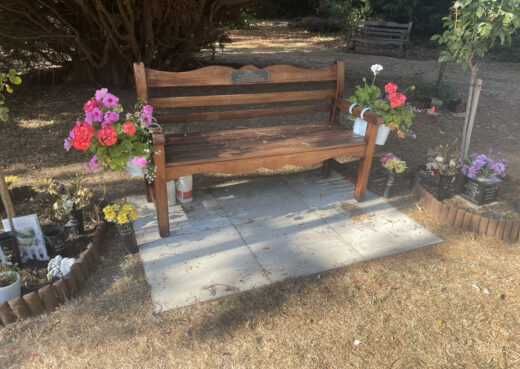 The Beverley Memorial bench adorned by flowers and personal tributes.