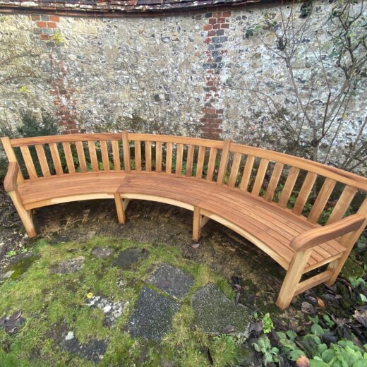Wide view of the bespoke curved bench set into The Master’s Garden, framed by historic flint walls and planting
