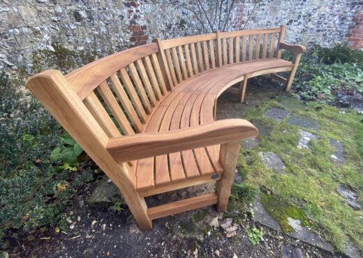 Curved York bench overlooking the pond and chapel at the Hospital of St Cross, Winchester, set within historic gardens