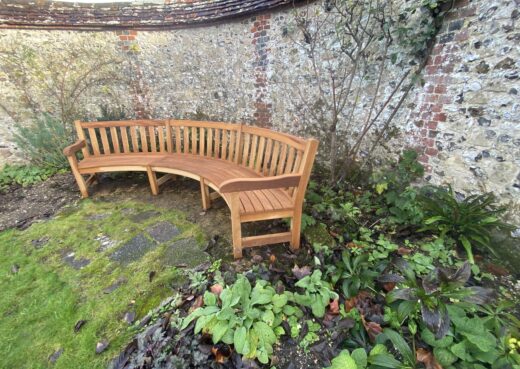 Curved York bench with shaped armrest overlooking The Master’s Garden, blending with historic stonework and planting