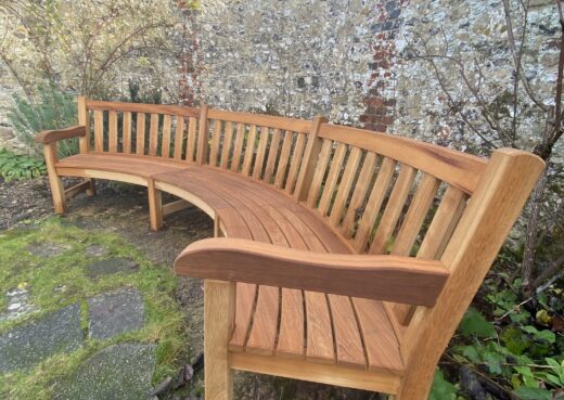 Full view of a 3.5 metre curved York bench positioned along a curved flint wall in The Master’s Garden at the Hospital of St Cross