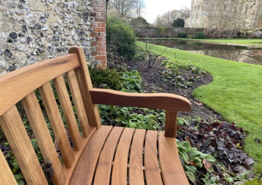 Bespoke curved York wooden bench installed in The Master’s Garden against a historic flint and brick wall at the Hospital of St Cross, Winchester