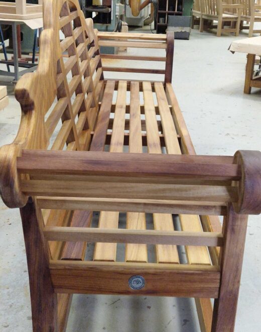 Lutyens-style teak garden bench viewed along the seat inside the Woodcraft workshop before delivery to The Hurlingham Club in London.