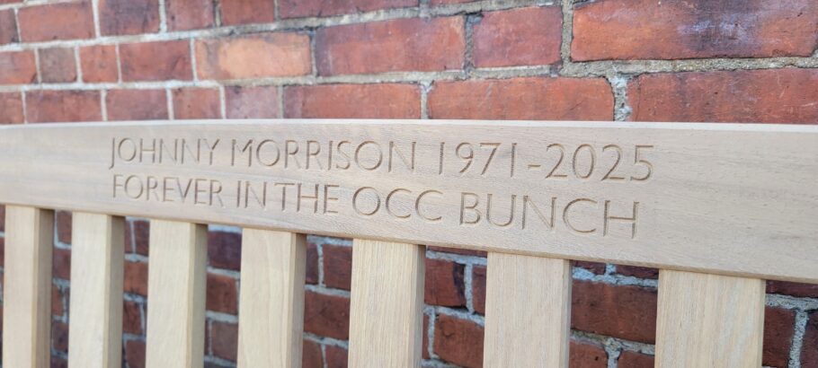 Close-up of the engraved memorial inscription on a handcrafted iroko York bench reading "Johnny Morrison 1971-2025 Forever In The OCC Bunch".