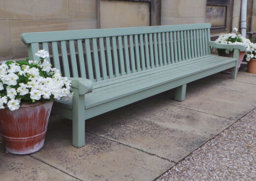 Side view of the Saltmarshe Bench with flower pots