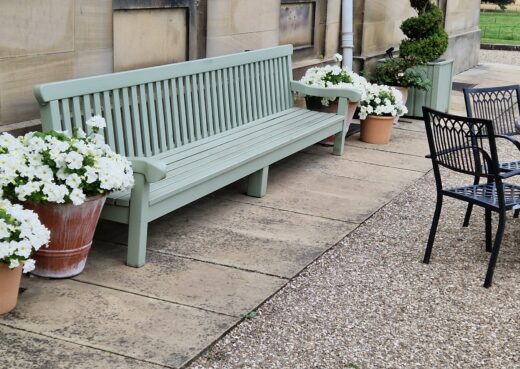 Eleven and a half foot wooden bench painted in a light teal green
