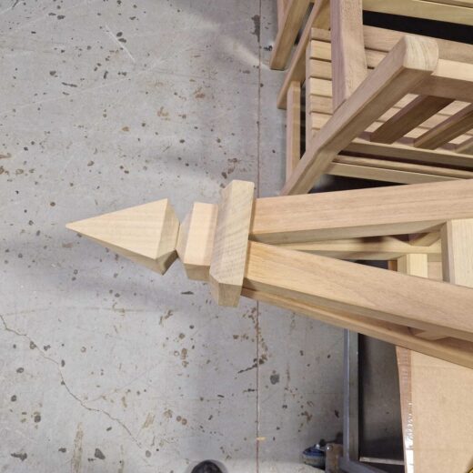 Top-down view of a wooden obelisk finial and upper frame on a workshop floor.