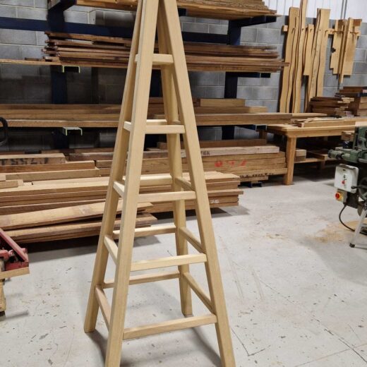 Partially assembled wooden garden obelisk standing in the workshop before finishing.