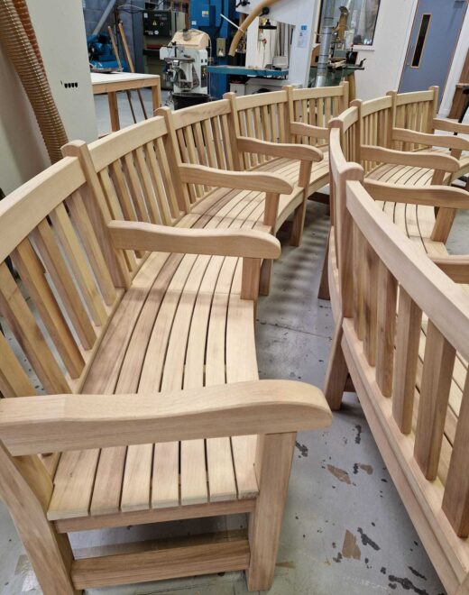 Curved wooden York benches lined up in the Woodcraft UK workshop after completion