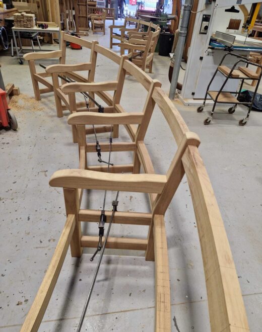 Curved York bench frames in mid-assembly at the Woodcraft UK workshop, showing the precision alignment and shaping required to create continuous curved seating for Greenwich Park