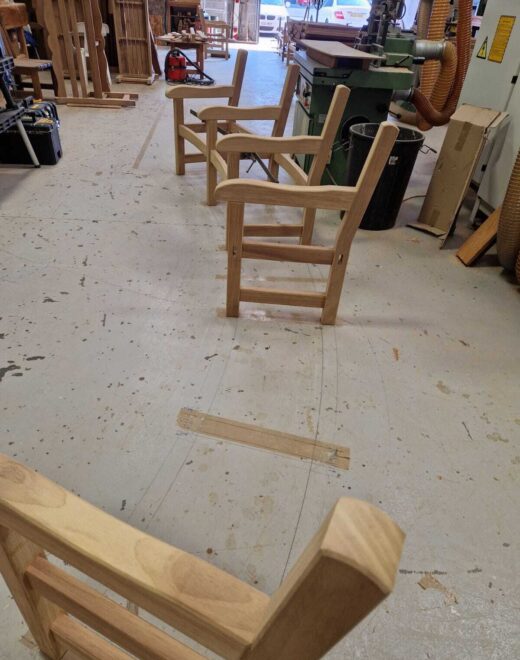 Partially assembled curved York bench frames secured with clamps in the Woodcraft UK workshop, showing the handcrafted shaping process before the seats are fitted