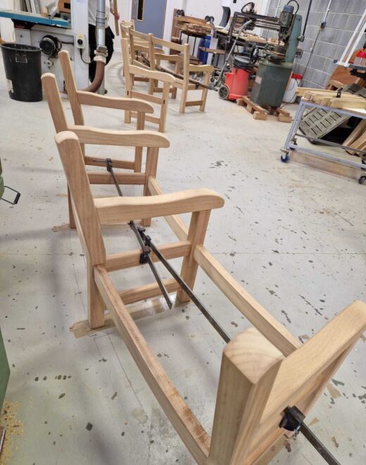 Handcrafted curved bench frames clamped during assembly in the Woodcraft UK workshop