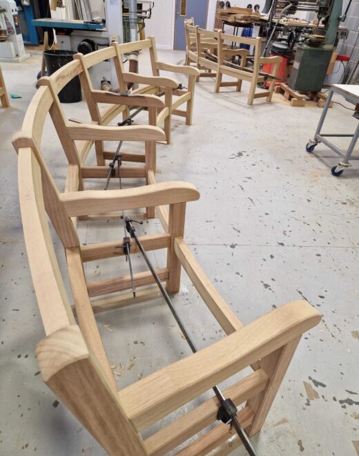 Curved wooden bench frames clamped during assembly in the Woodcraft UK workshop