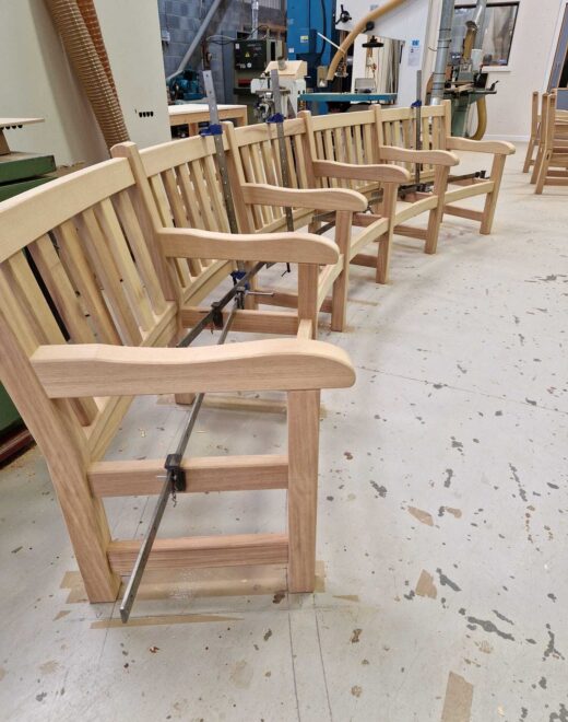 Unfinished curved York benches standing complete in the Woodcraft UK workshop, ready for transport and installation at Greenwich Park in London