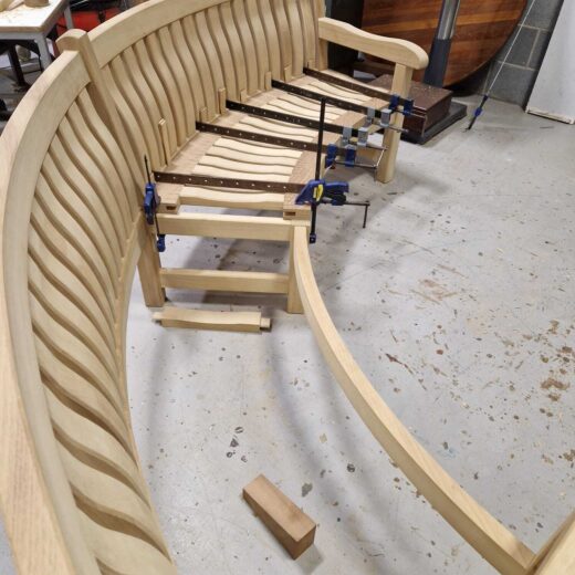 Partially assembled curved bench showing seat panel installation.