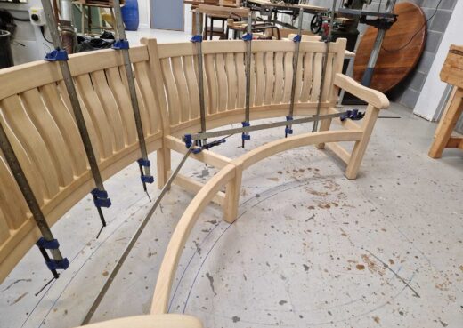 Back slats being clamped to the curved bench frame during construction.