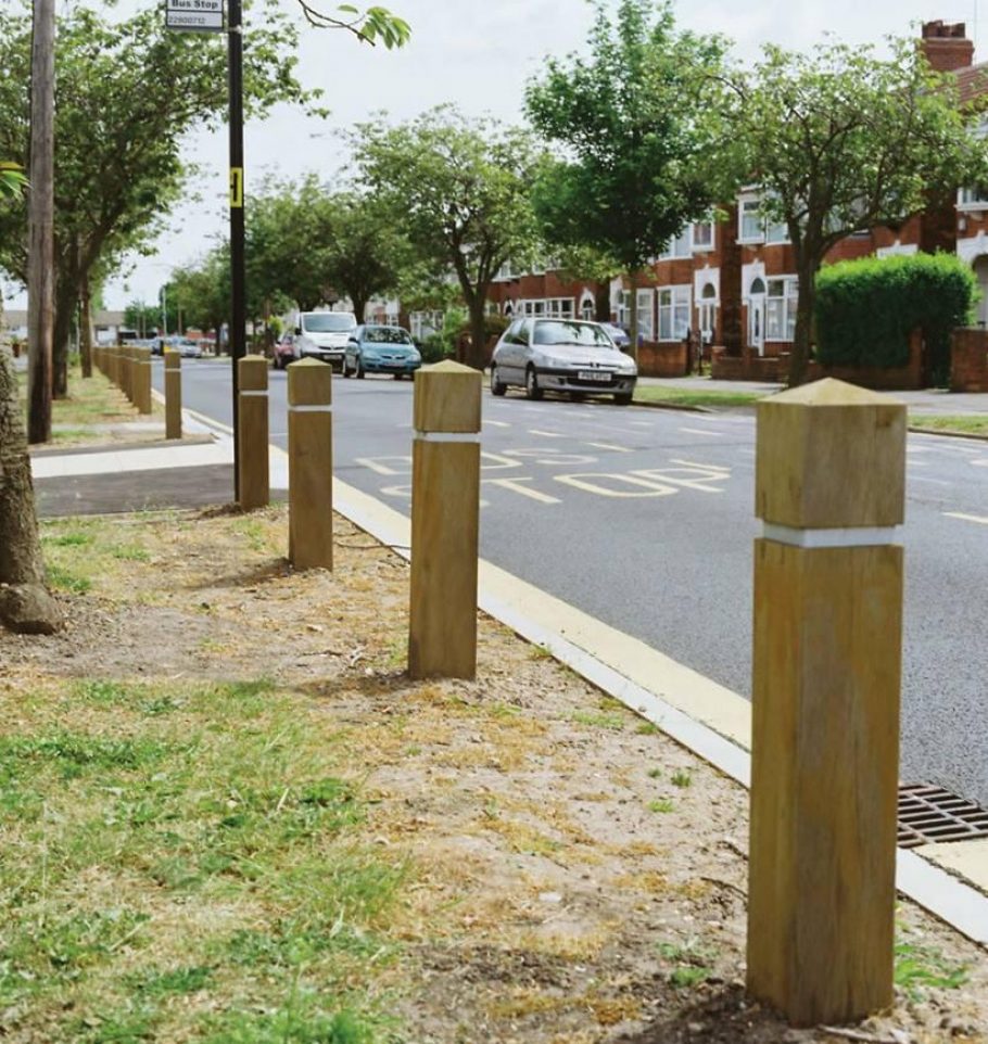 Roadside wooden bollards protecting grass verges from car parking