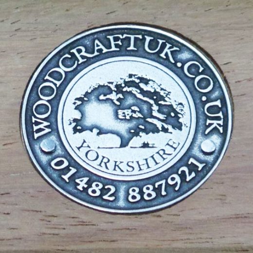 Steel embossed badge inset into wood