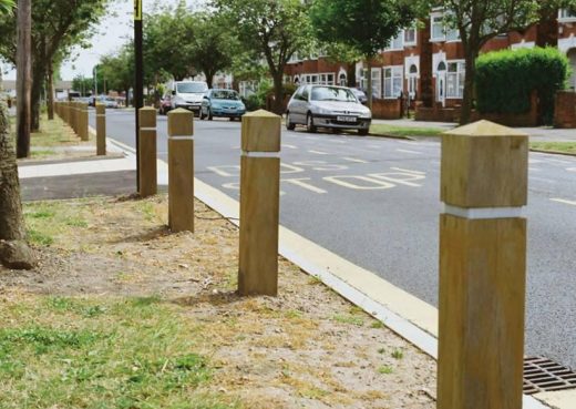 Roadside wooden bollards protecting grass verges from car parking